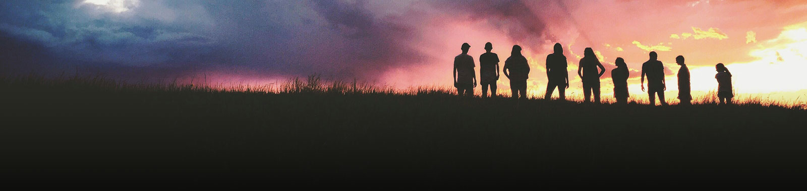 Header image featuring the silhouette of people standing on a hill at sunset