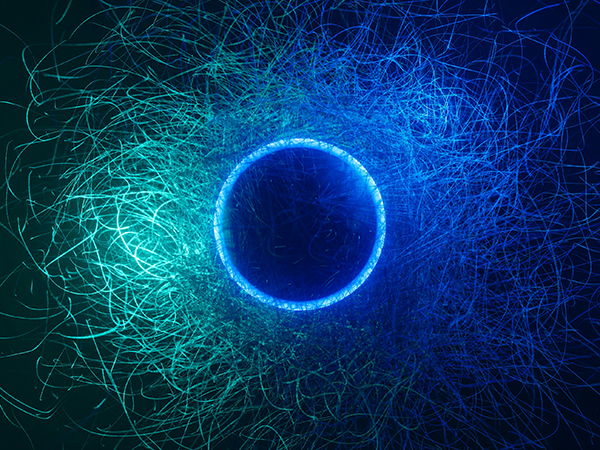 group-lab-quantum-illuminated-circle Abstract graphic of a blue-tinged circle surrounded by trails of light in varying shades of green and blue against a black background