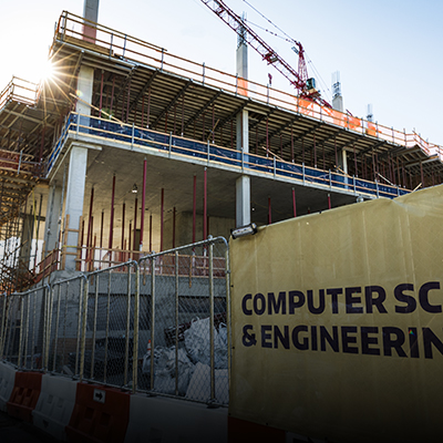 The Bill & Melinda Gates Center is shown under construction, with no walls and fencing around the site and a partially visible sign saying Computer Science & Engineering