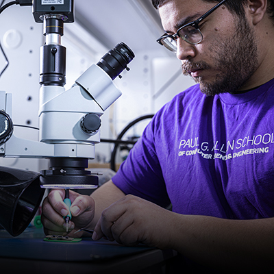 A student in an Allen School t-shirt building a biodegradable circuit