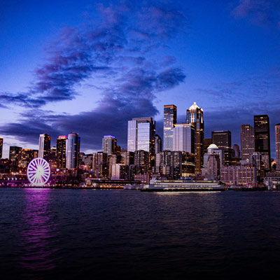 Night time view of the Seattle skyline with the Great Wheel lit up in purple lights.