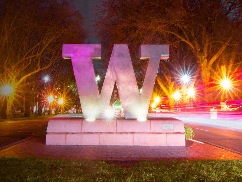 Bronze W statue with pink and gold lighting.