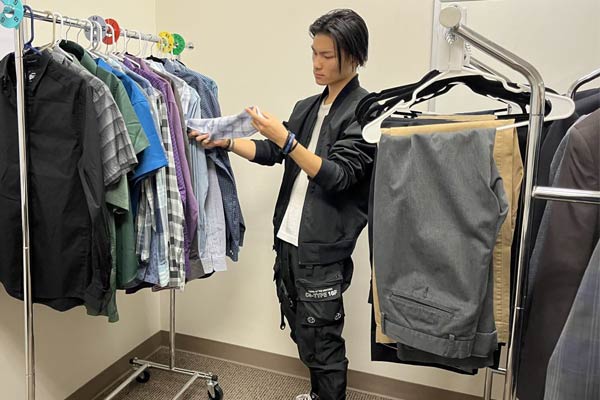 Young student looking at a wrack of suit jackets at the Husky Career Closet resource.