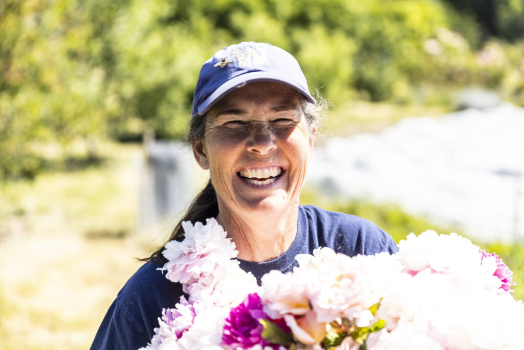 Mental Healthcare for All Grand Challenge: A smiling woman holding a large boquet of fresh picked flowers.