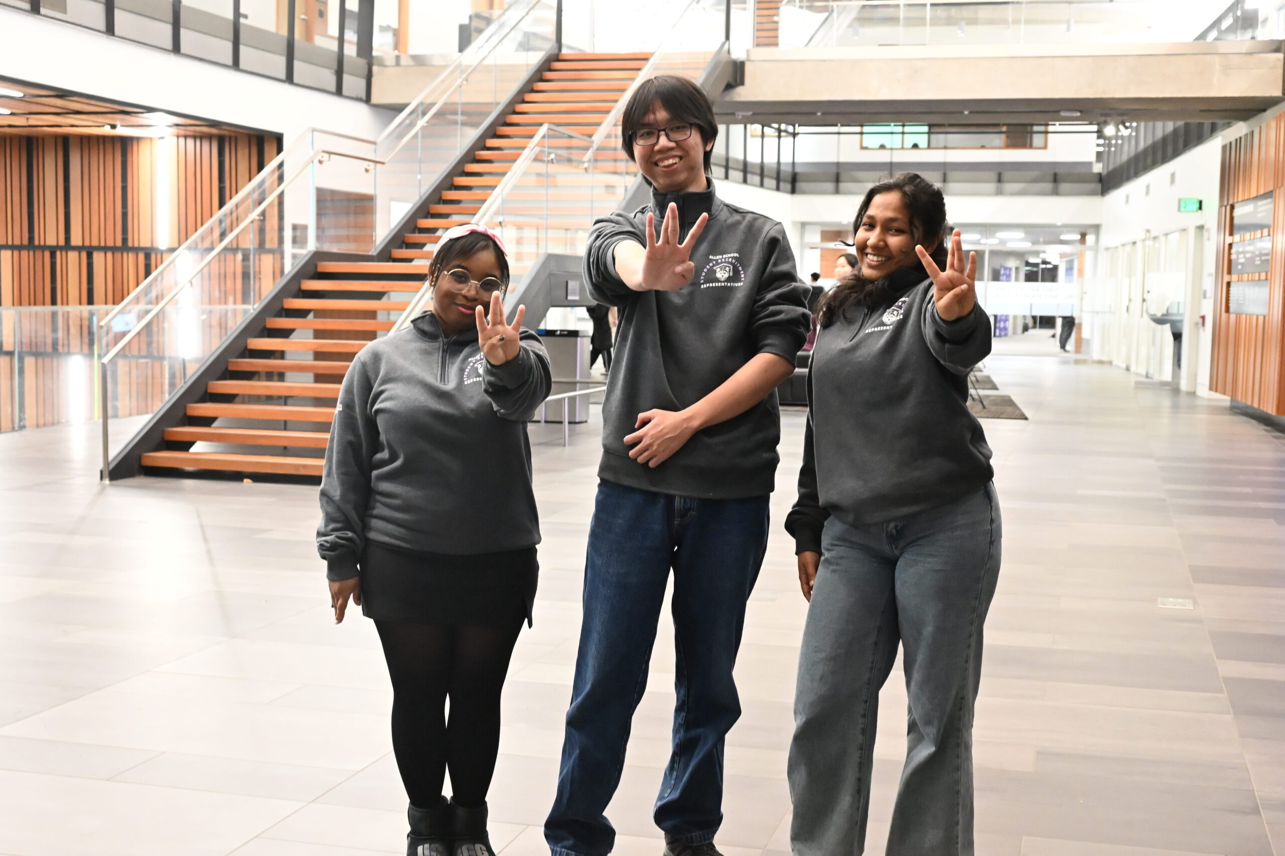 Three transfer students pose with their "Dubs Up" fingers spelling out a W.
