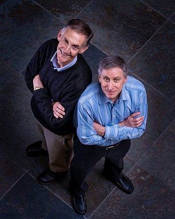 Portrait of Ed Lazowska and Hank Levy standing shoulder to shoulder with arms folded and viewed from above
