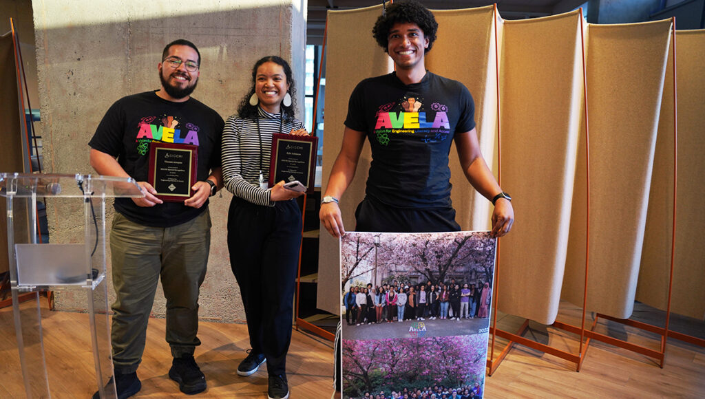 Vicente Arroyos, Leilani Battle and Kyle Johnson accept the SIGCHI Special Recognition for their work with AVELA. Kyle holds a poster of a group photo of all other AVELA members.