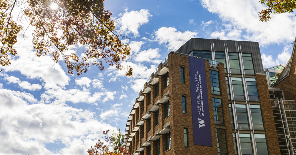 The exterior of the Allen School building is shown on a sunny Fall day against a blue sky dotted with clouds.
