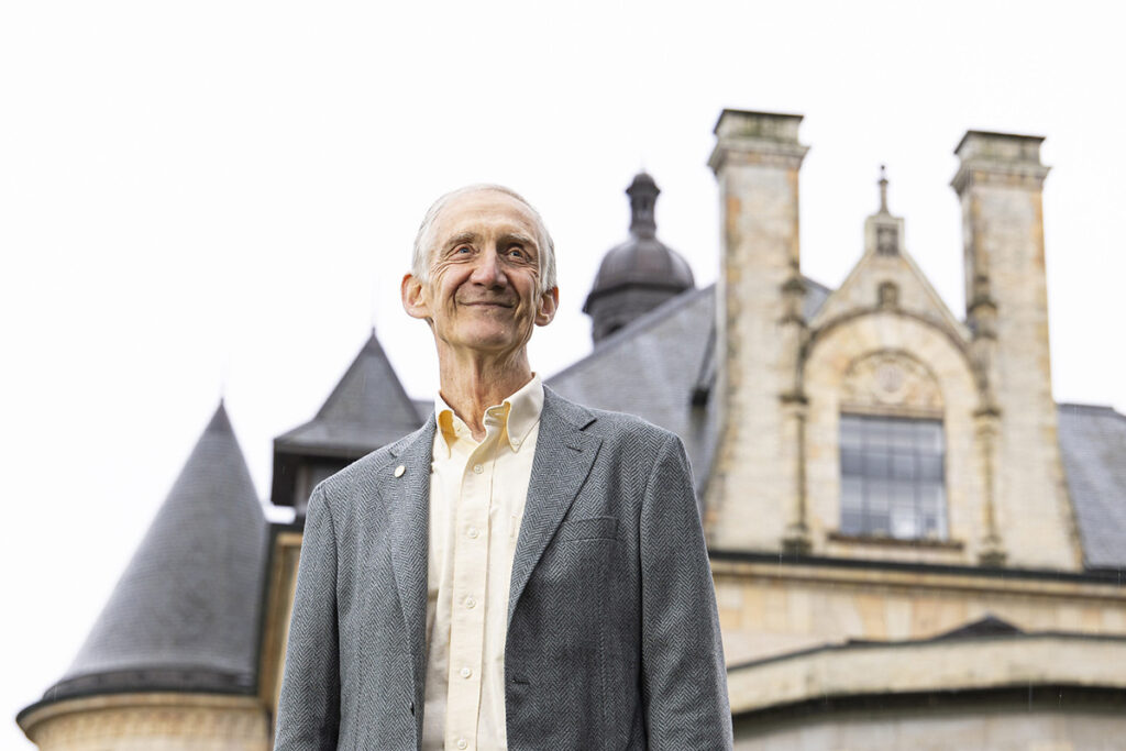 Ed Lazowska standing in front of an old university building that resembles a castle with turrets and stained glass