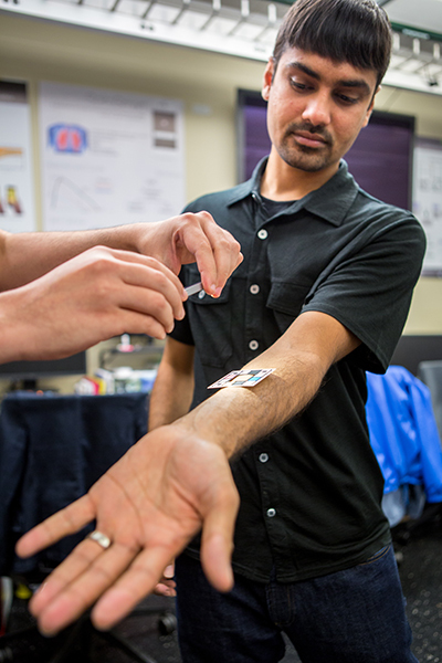 Shwetak Patel extends out his arm, showing a color guide resting on it which can help detect someone's bilirubin levels.