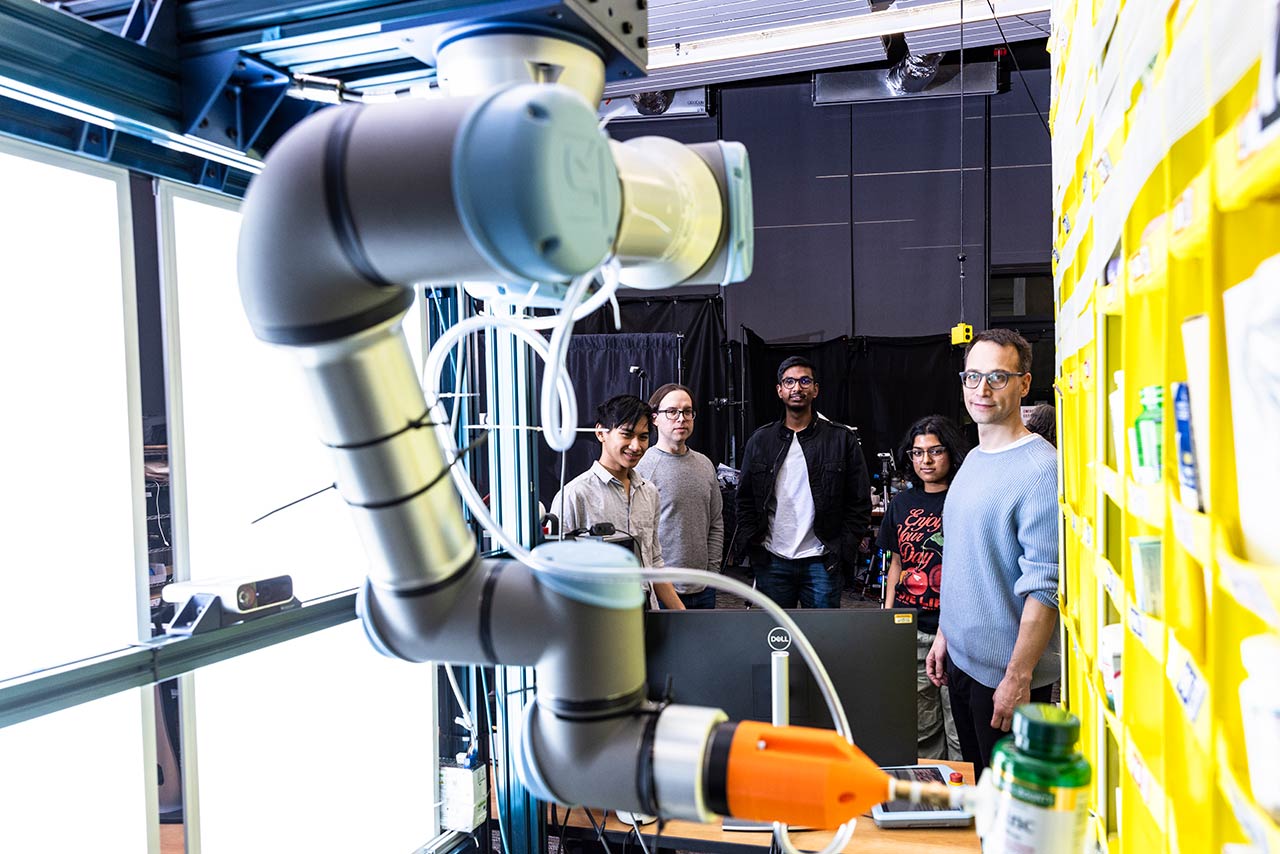 robot arm with students and professor in the background