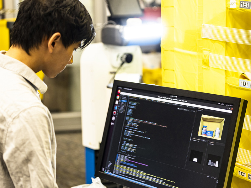 Student in a robotics lab reviewing code on a computer screen.