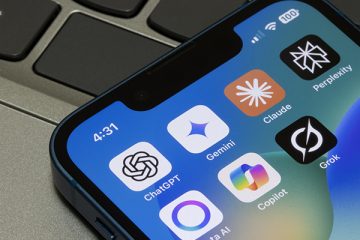 The image zooms in on a smart phone laying on top of a laptop keyboard. The smartphone screen shows various AI apps including ChatGPT, Gemini, Claude, Perplexity, Meta AI, Copilot and Grok.