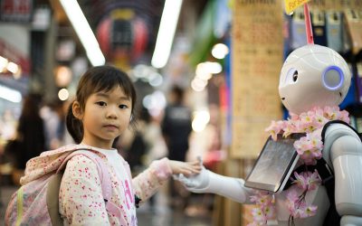 A small child wearing a hoodie and backpack holds hands with a robot humanoid.