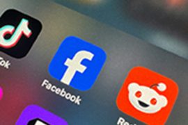 A close-up of a smartphone screen showing various social media icons such as Reddit, Facebook and Twitter.