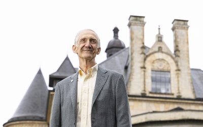 Ed Lazowska standing in front of an old university building that resembles a castle with turrets and stained glass