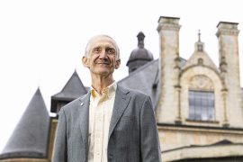 Ed Lazowska standing in front of an old university building that resembles a castle with turrets and stained glass