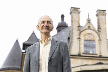Ed Lazowska standing in front of an old university building that resembles a castle with turrets and stained glass
