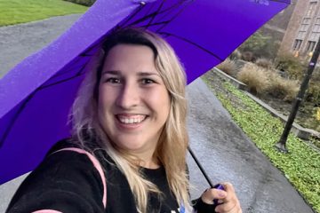 Kate Glazko smiles and holds a purple umbrella while taking a selfie