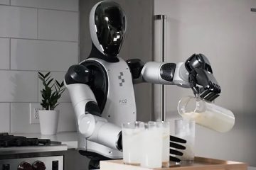A humanoid robot with a blank black face and mostly white body stands in a kitchen pouring a beverage from a pitcher