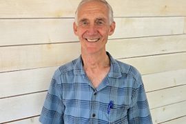 Casual portrait of Ed Lazowska pictured against whitewashed shiplap