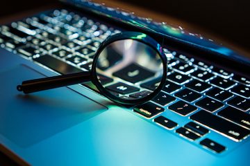 A magnifying glass positioned over the keyboard of a laptop computer