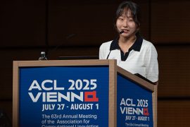Sewon Min speaking into a microphone at a podium labeled ACL 2025 Vienna