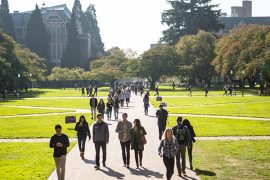 Students walking on the brick path of a sunlit UW quad framed by trees